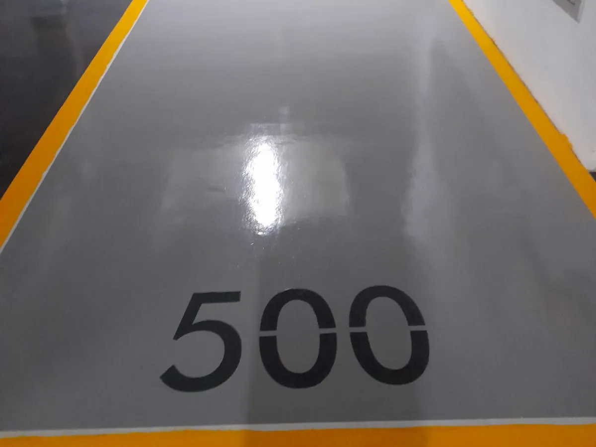 Vaga de garagem pintada pela MG, piso cinza acetinado com moldura amarela e numeração 500 estampada